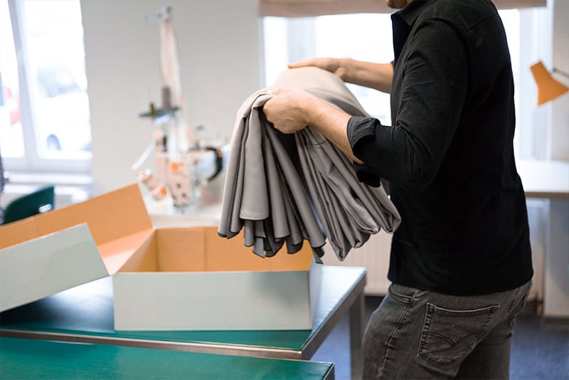 Fertig genähte graue Vorhänge werden in einen Karton gelegt