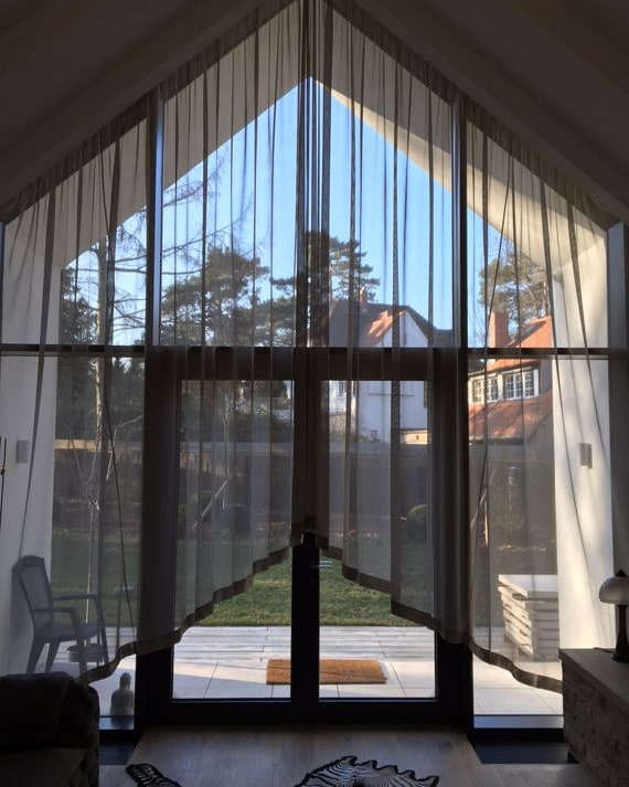 Dasselbe Giebelfenster mit transparenten Vorhängen über die ganze Höhe