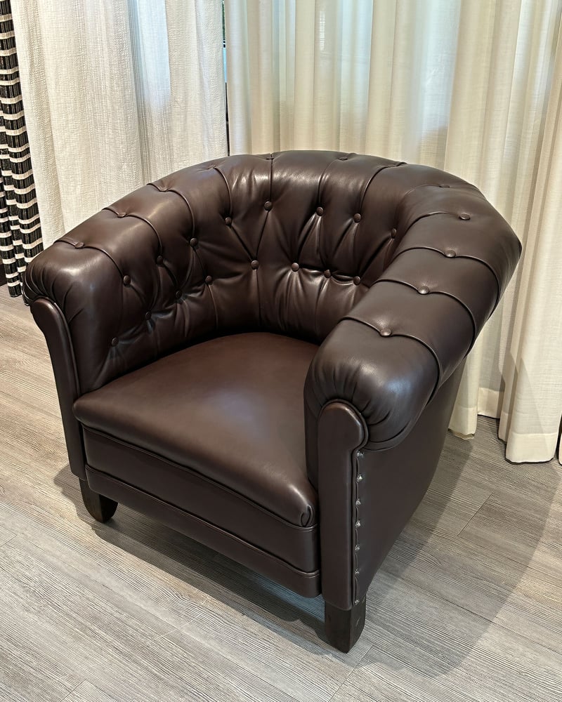 Derselbe Clubsessel nach der Aufarbeitung, neu bezogen in Braun mit Knopfheftung.