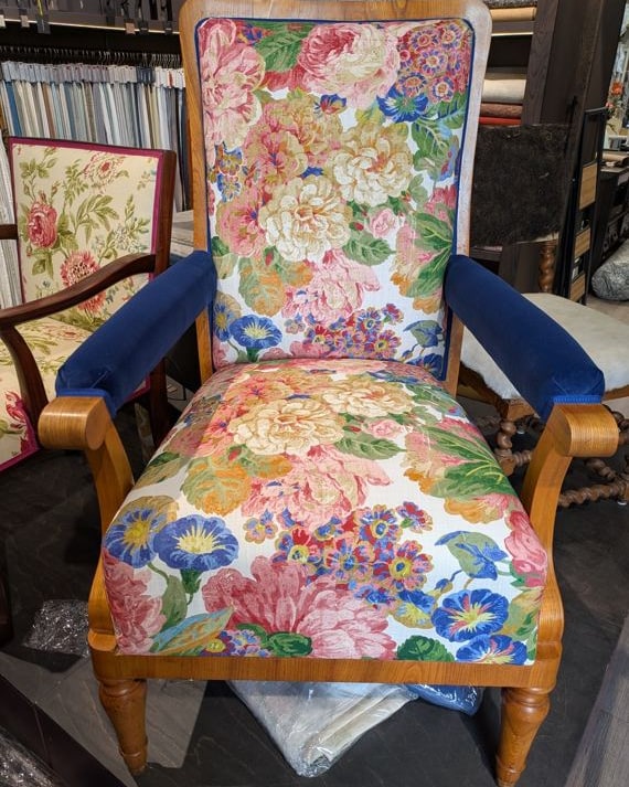 Derselbe Sessel nach dem Neubezug: Blumenstoff an Sitz und Rücken, die Armlehnen in blauem Samt.
