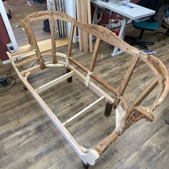 Dasselbe Sofa, abgetragen bis auf das Holzgestell, mit hell eingesetzten neuen Holzteilen